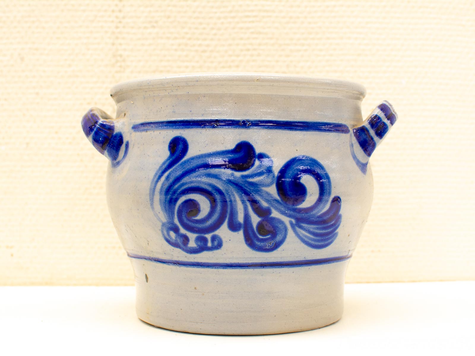 Charming gray ceramic pot with intricate blue designs and functional handles for storage or decor.