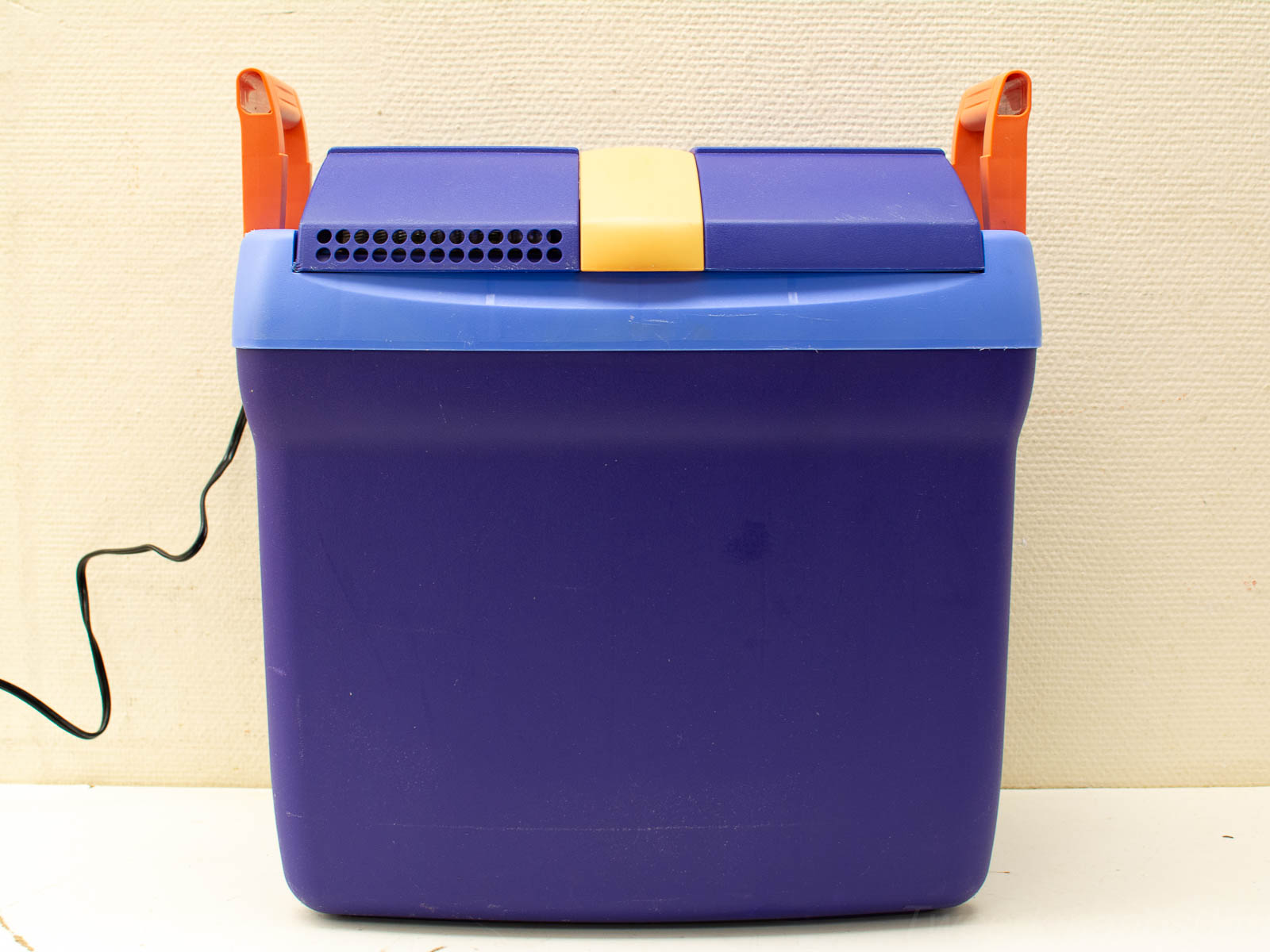 Vibrant purple electric cooler with blue lid, yellow stripe, and orange handles for outdoor fun.