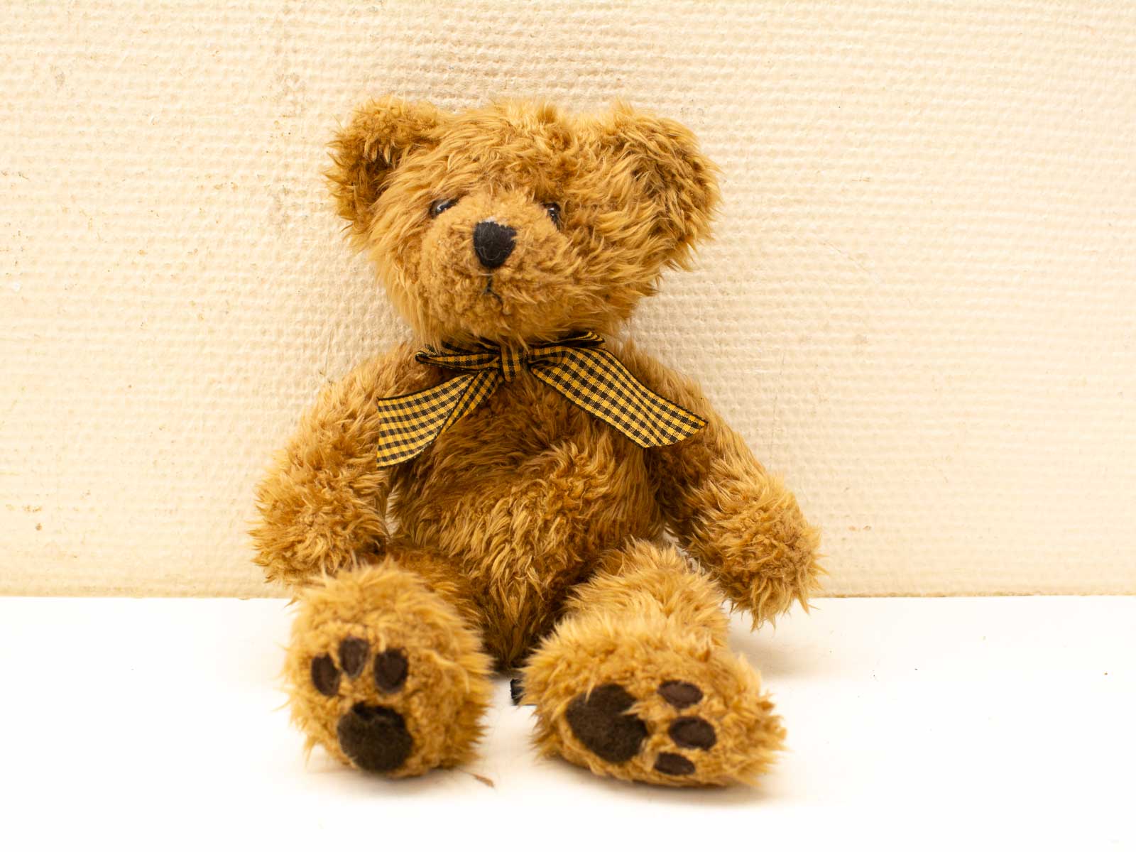 Charming teddy bear with a vintage bow tie, perfect for cuddling and nostalgic comfort.