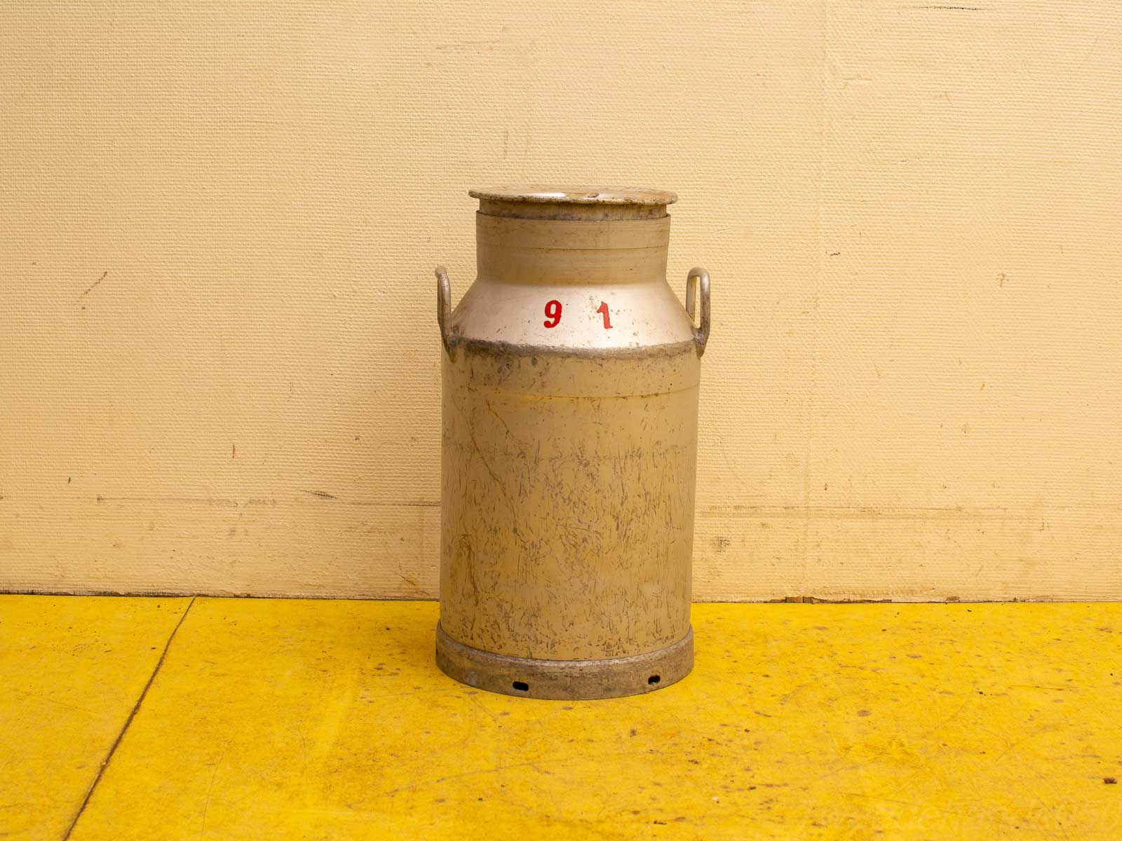 Vintage milk can with red numbers, distressed silver finish, perfect for rustic decor enthusiasts.