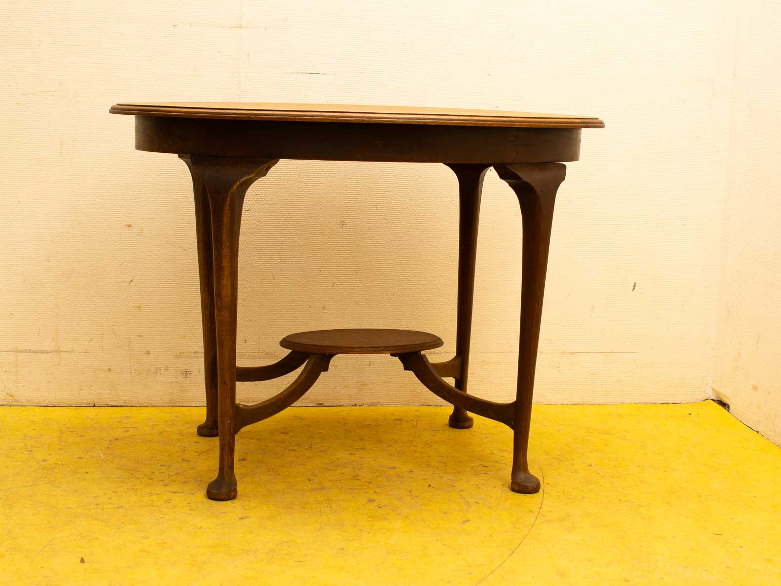 Elegant vintage wooden table with oval top and round shelf, ideal for cozy living spaces.