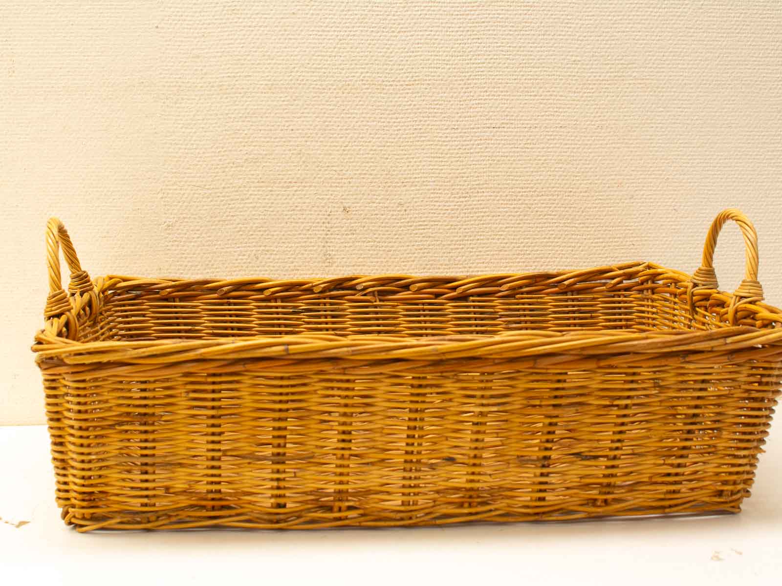 Rustic wicker basket with curved handles for stylish storage and home decor.