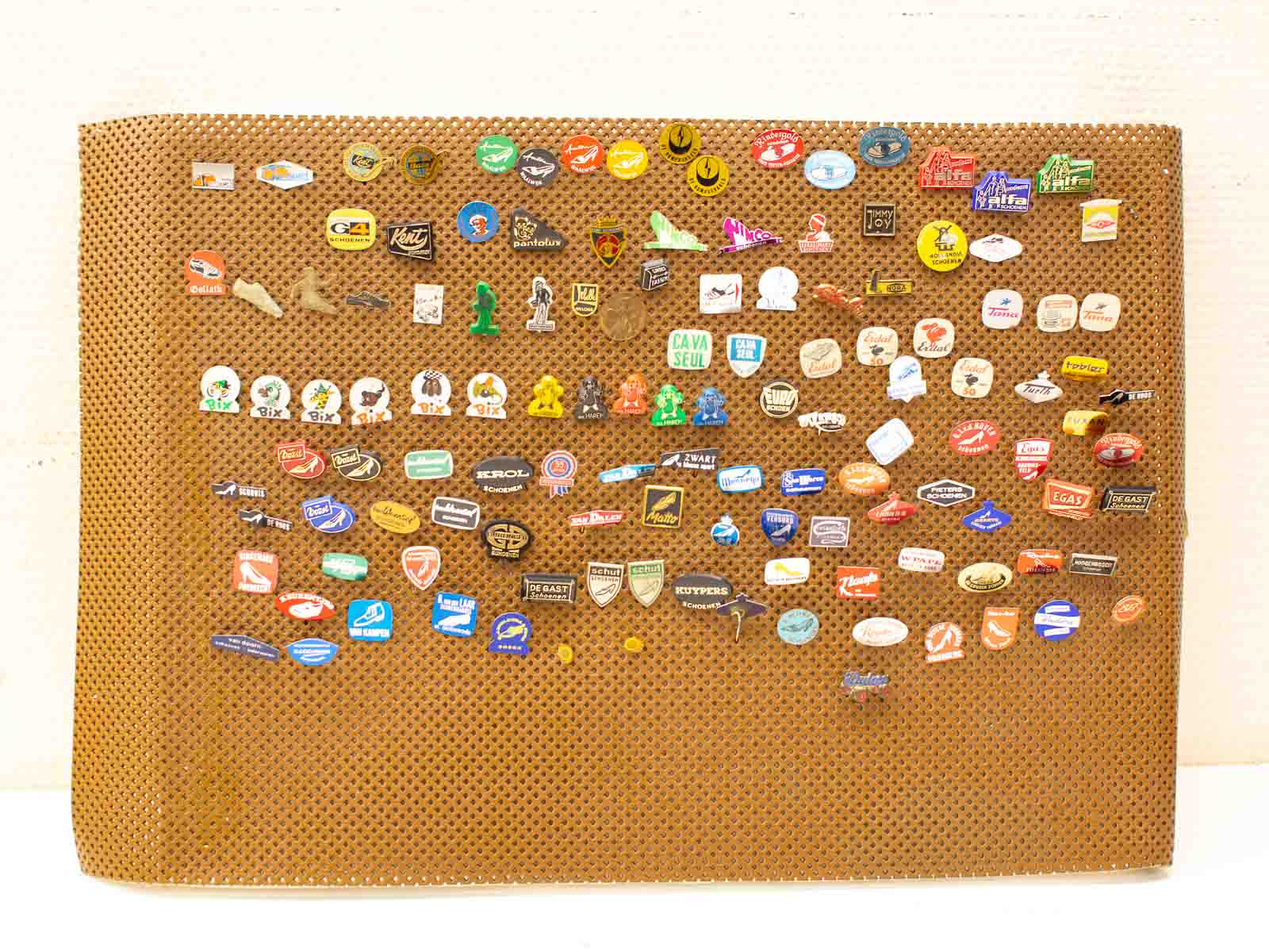 Colorful vintage enamel pins showcasing memories and stories on a textured brown background.