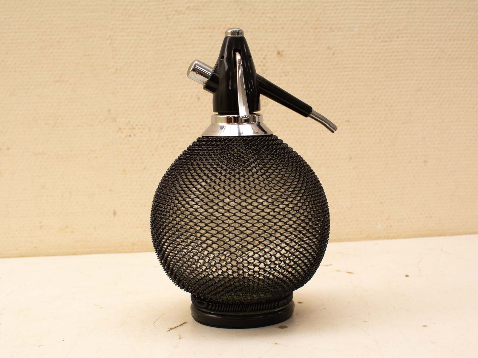 Vintage soda siphon with sleek chrome accents and black mesh, perfect for stylish carbonation.