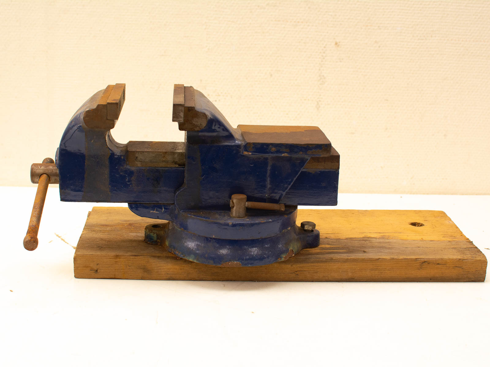 Durable vintage blue bench vise on wooden base, perfect for workshops and DIY projects.