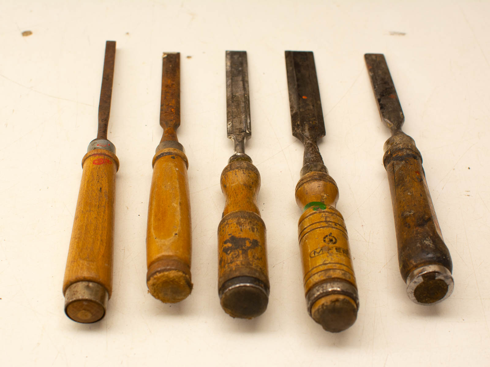 Vintage wooden chisels set for woodworking, featuring unique widths and rustic handles.