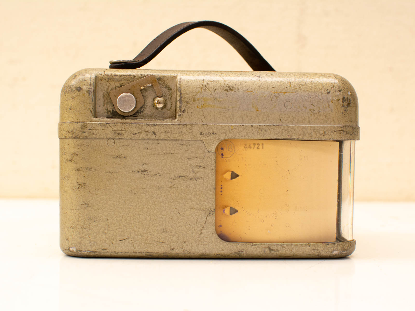 Vintage measuring instrument in worn olive metal case with leather strap, ideal for collectors.