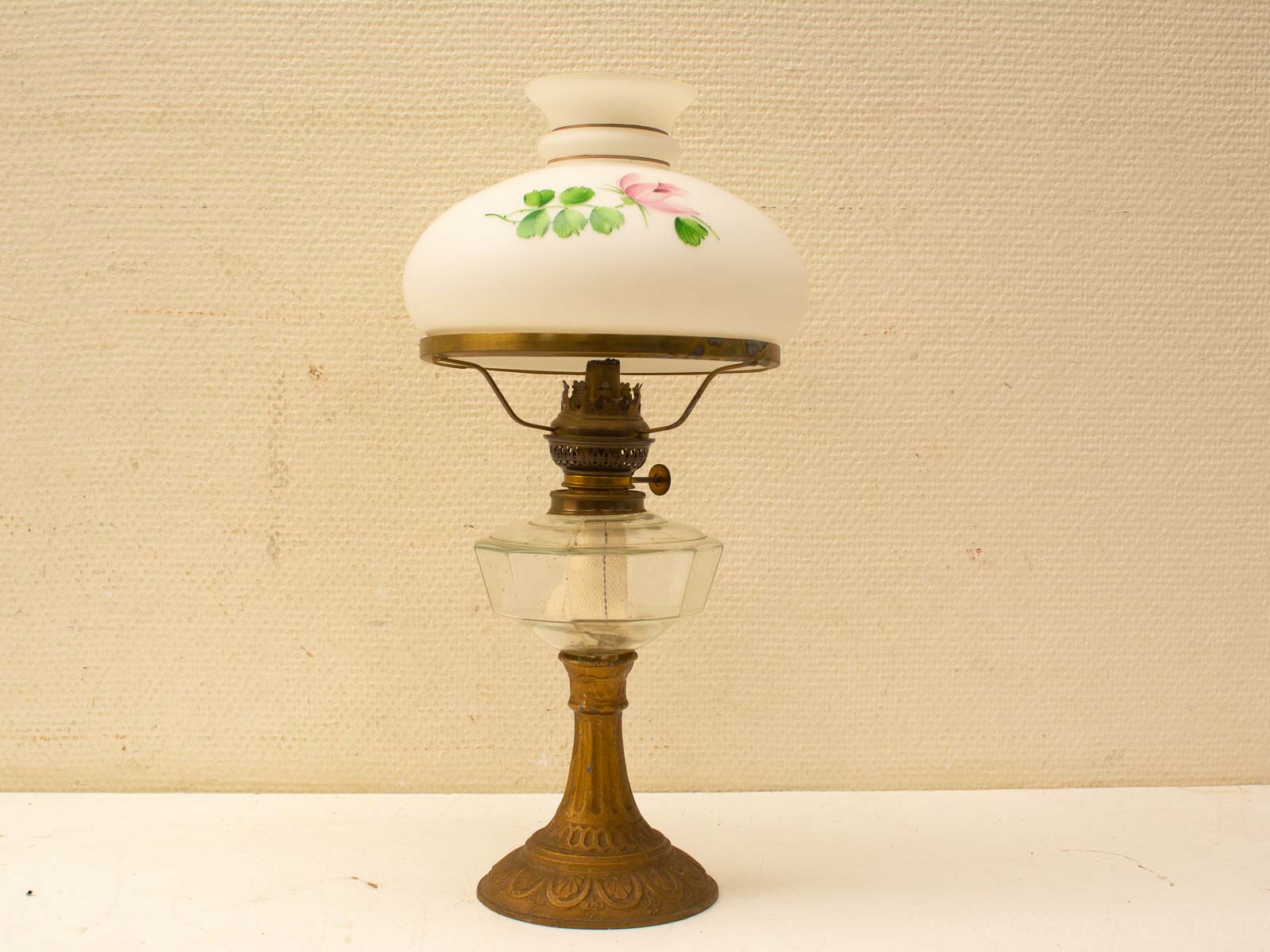 Elegant vintage kerosene lamp with ornate bronze base and hand-painted rose shade for nostalgic decor.