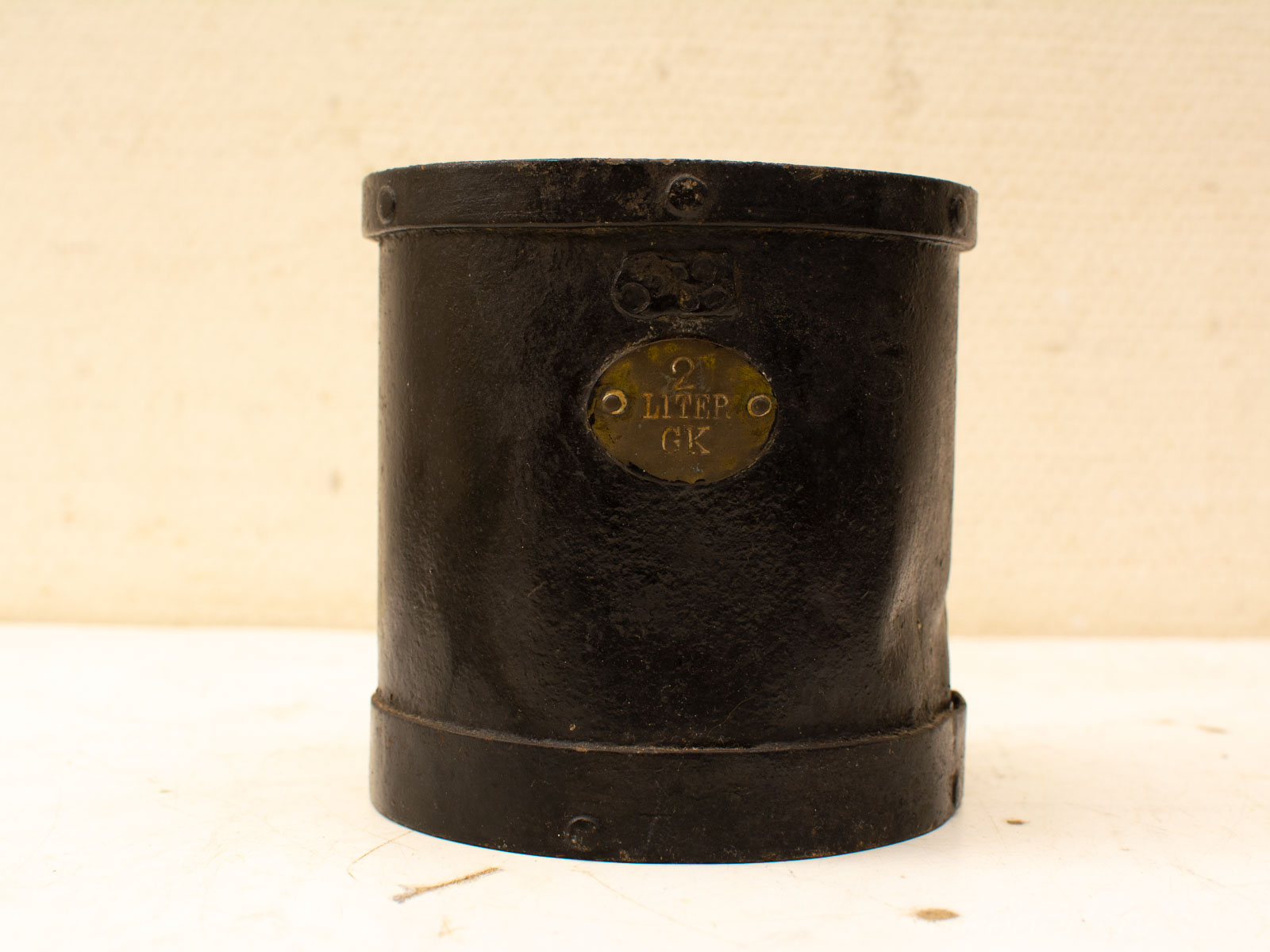 Vintage black metal 2-liter measuring container with brass plaque for functional elegance.