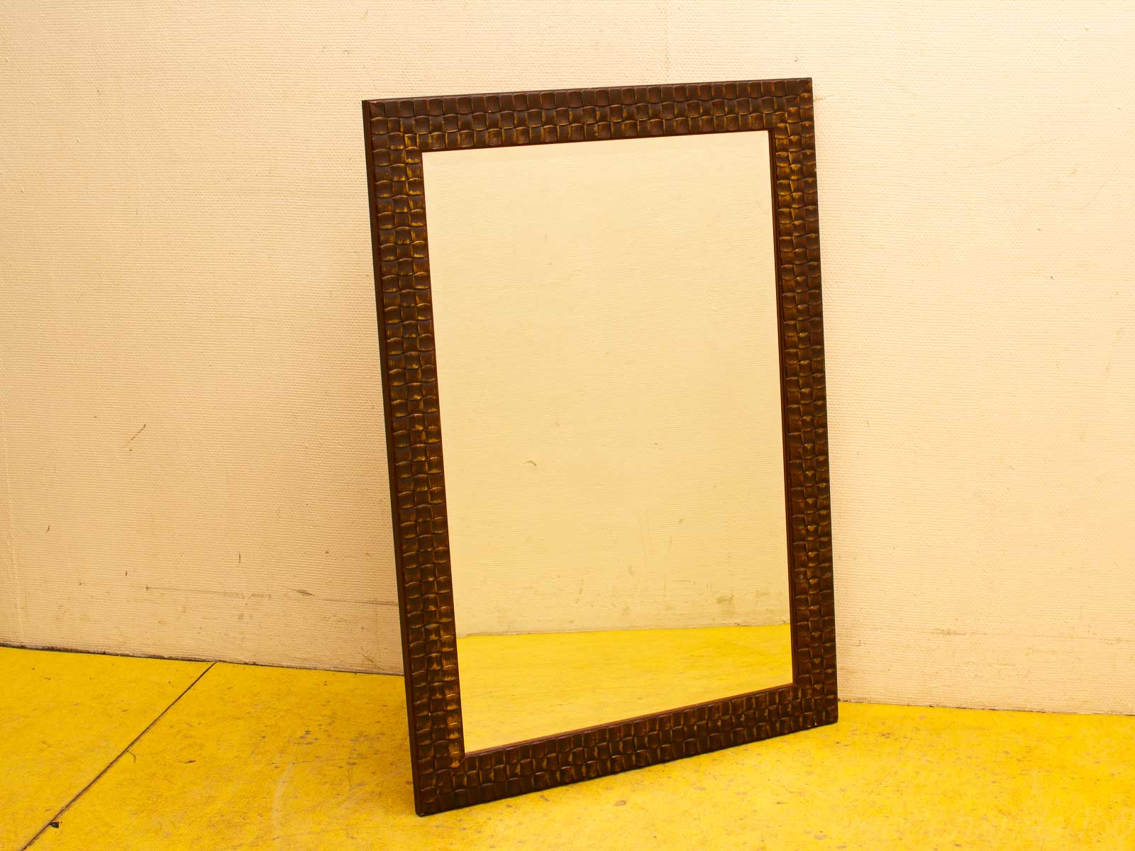 Elegant vintage mirror with intricate frame on cheerful yellow floor, adding charm to any decor.