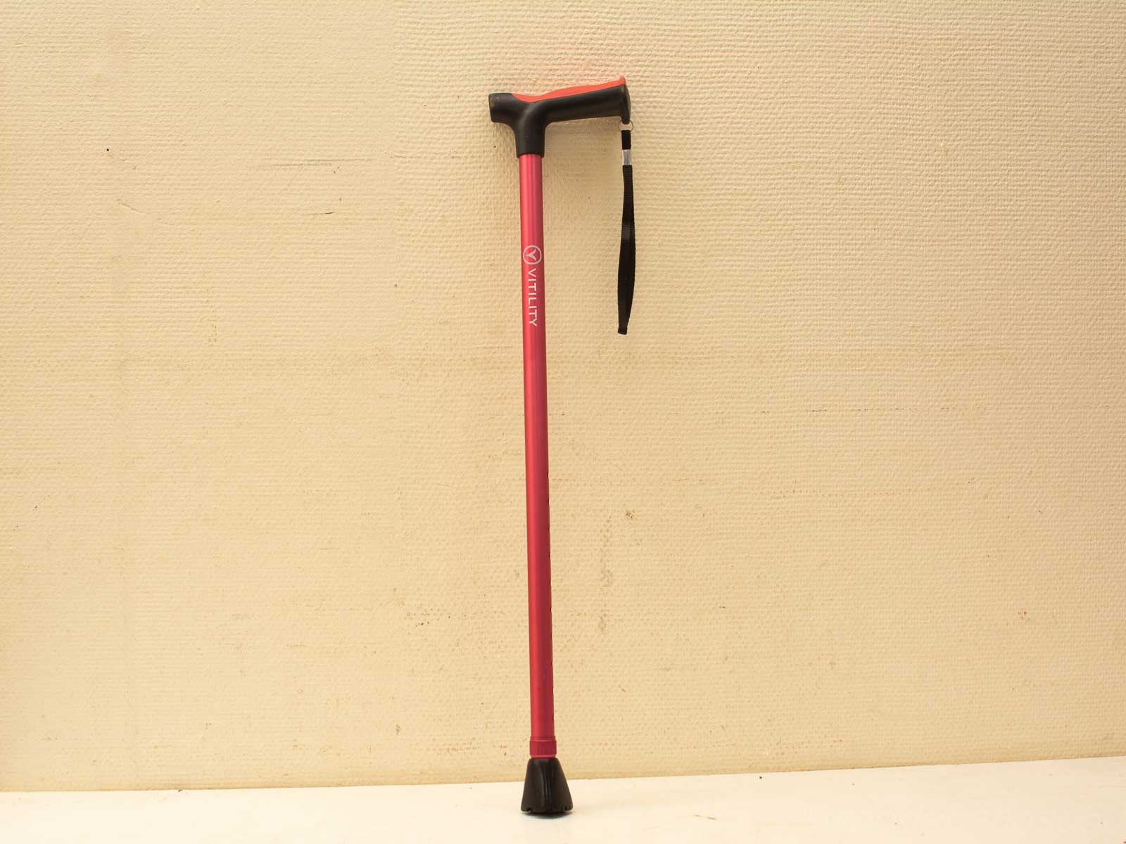 Stylish pink walking cane with black grip, rubber tip for safety and support.