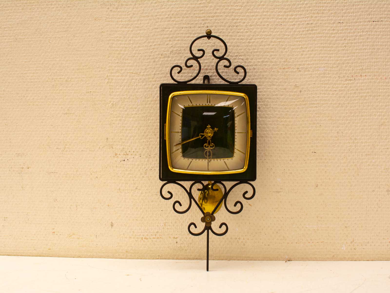 Elegant vintage wall clock with gold accents and artistic iron base for stylish interiors.