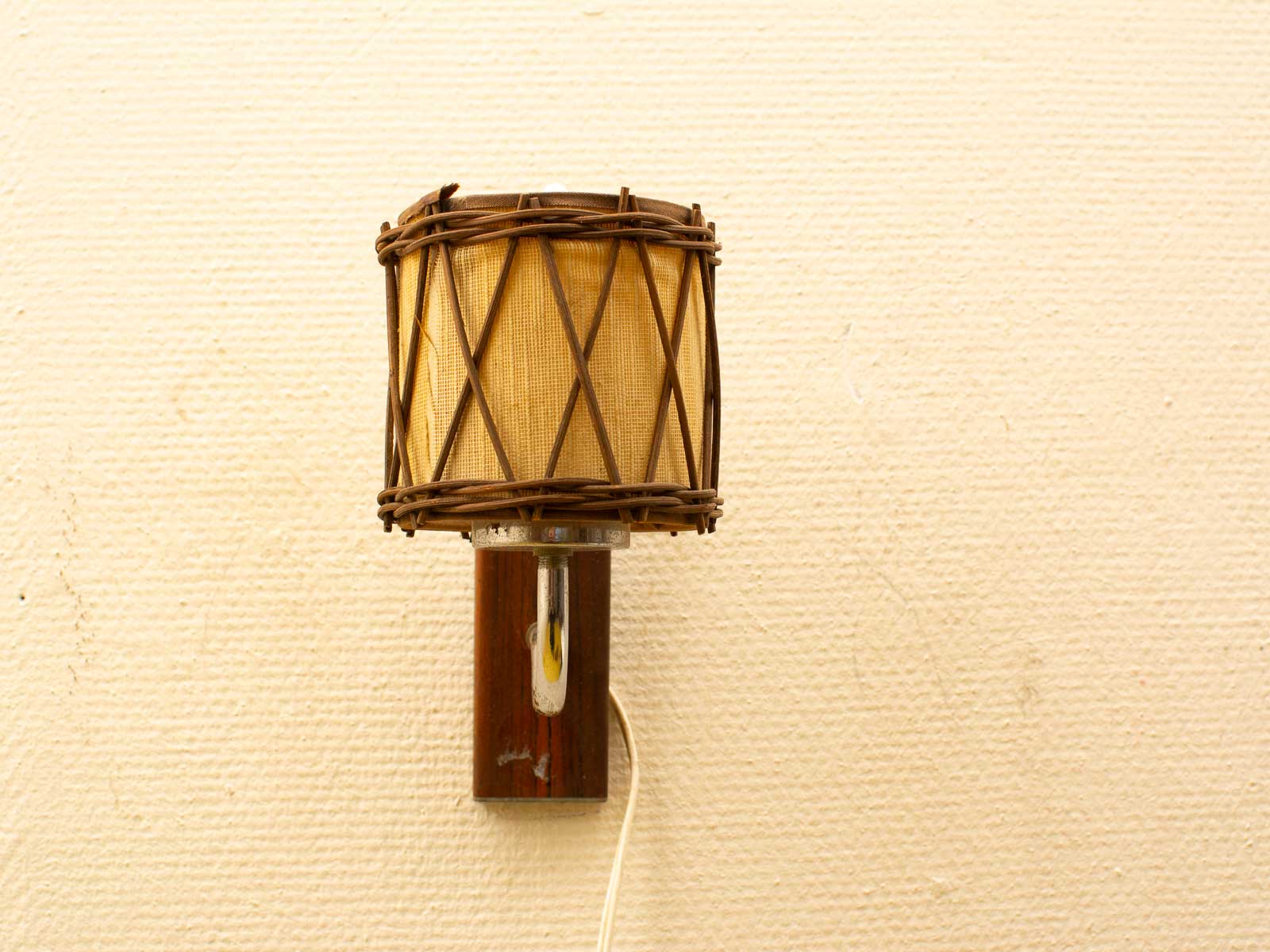 Rustic wall lamp with woven shade and wooden base for a warm, inviting atmosphere.