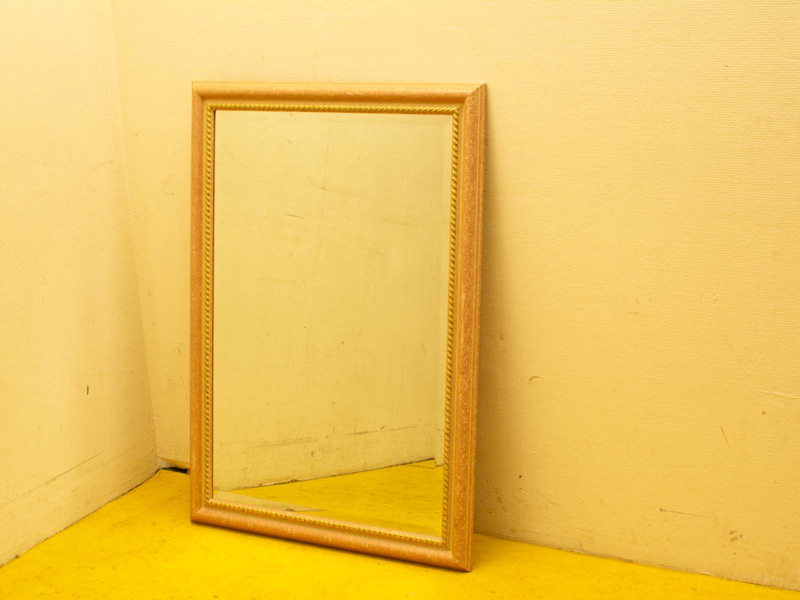 Charming vintage wooden mirror against a warm yellow wall, adding cozy character to any room.